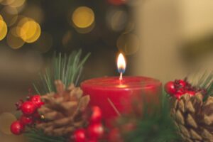 Red candle with pine cones and blurred bokeh lights, perfect for holiday decor inspiration.